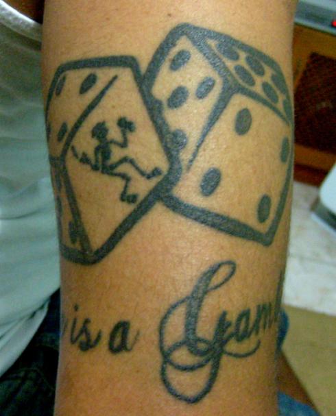 Skelly in dices and "Lifes is a Gamble" tatooed on arm - Marcel f...